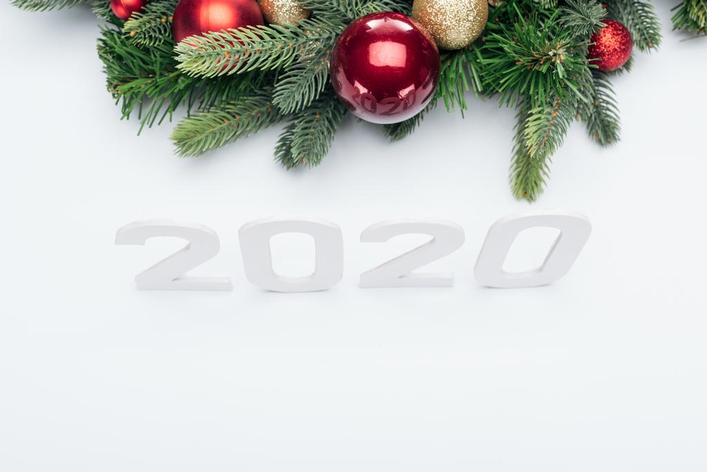 top view of paper 2020 numbers near Christmas tree wreath with baubles on white background - Photo, Image