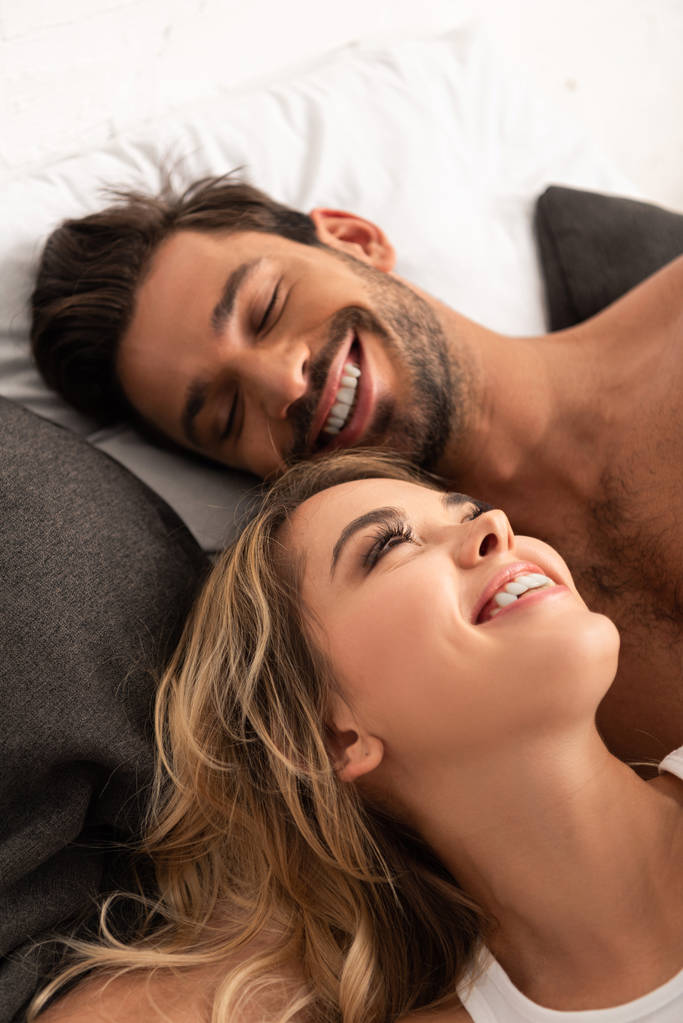 όμορφο χαμογελαστό ζευγάρι ξαπλωμένο στο κρεβάτι το πρωί  - Φωτογραφία, εικόνα