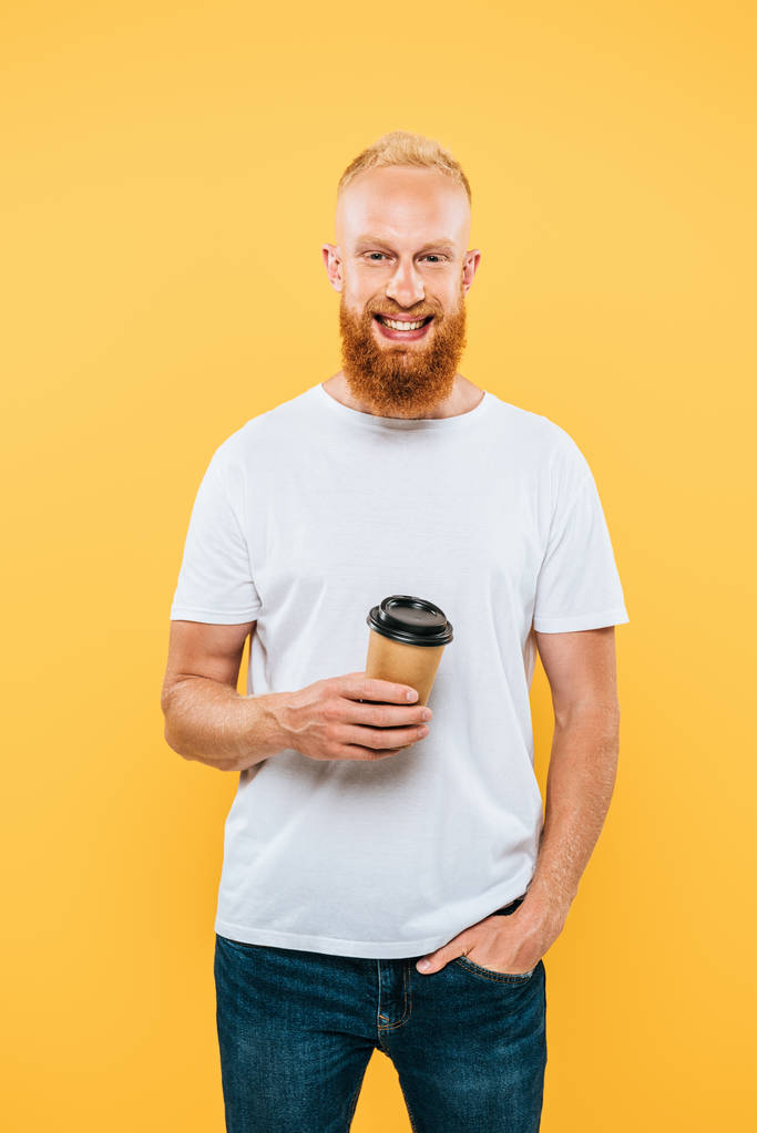 handsome smiling man in t-shirt holding coffee to go, isolated on yellow - Photo, Image