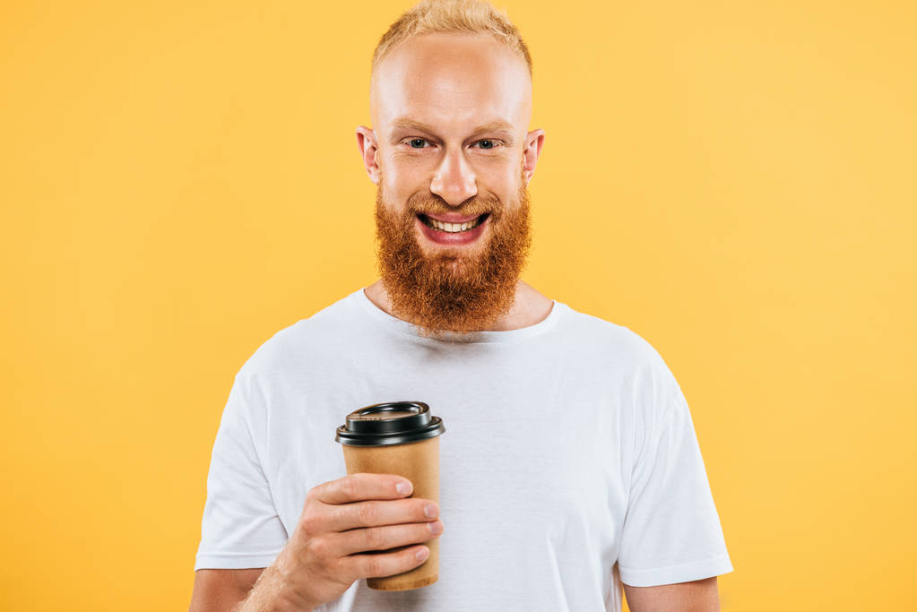 Vidám szakállas férfi pólóban, kezében kávé elvitelre, elszigetelt sárga - Fotó, kép