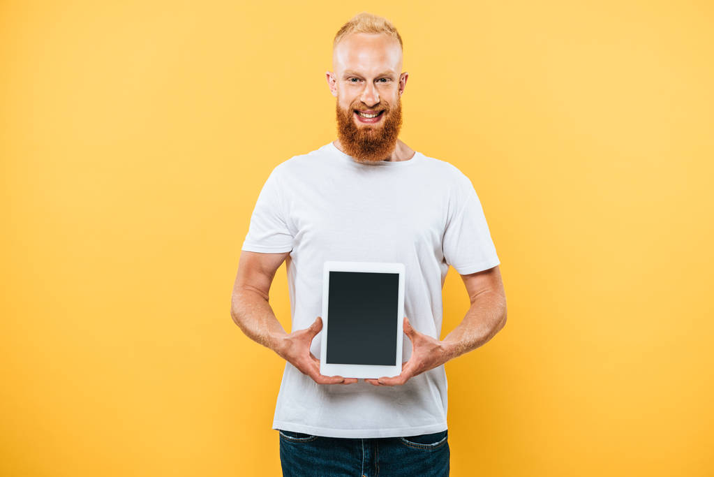 fröhlicher Mann zeigt digitales Tablet mit leerem Bildschirm, isoliert auf gelb - Foto, Bild