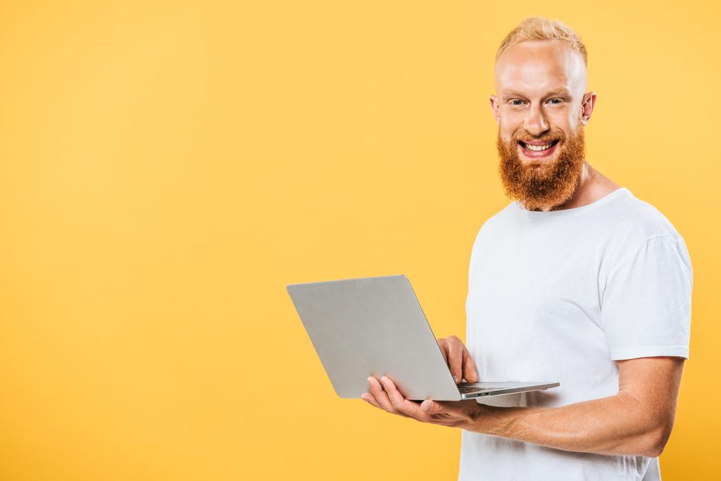 homme barbu souriant utilisant un ordinateur portable, isolé sur jaune
 - Photo, image