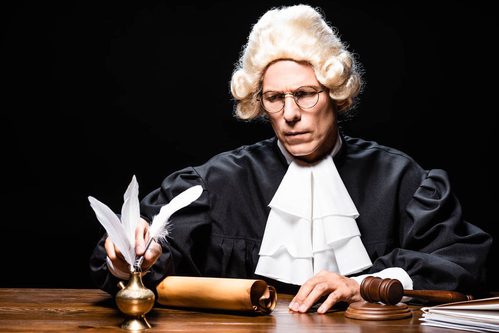 δικαστής με δικαστική ρόμπα και περούκα που λαμβάνει φτερό απομονωμένο σε μαύρο - Φωτογραφία, εικόνα