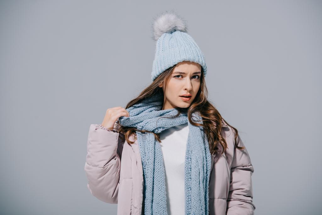стильная девушка, позирующая в теплом пальто, вязаной шляпе и шарфе, изолированная на сером
 - Фото, изображение