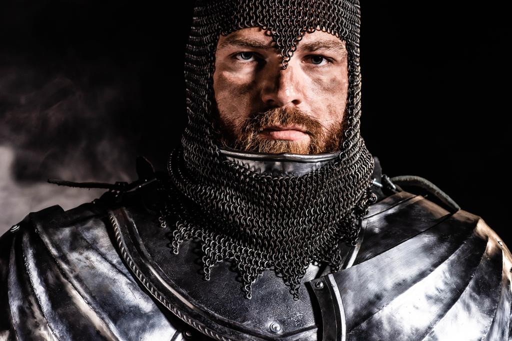 handsome knight in armor looking at camera on black background - Photo, Image