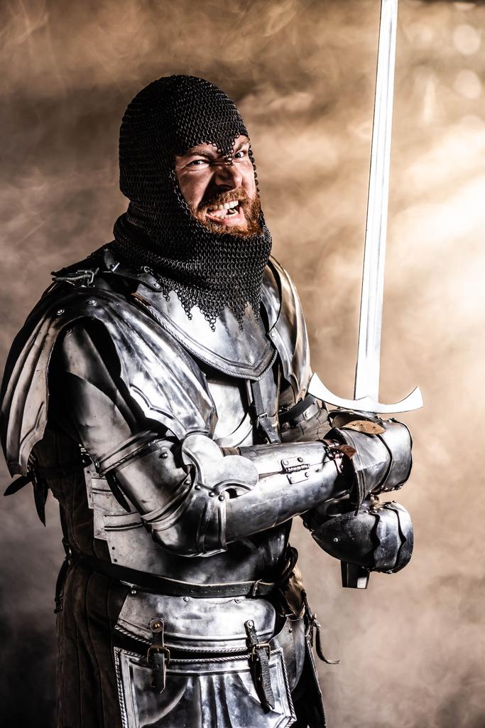 pohledný rytíř v brnění drží meč a boj na černém pozadí - Fotografie, Obrázek