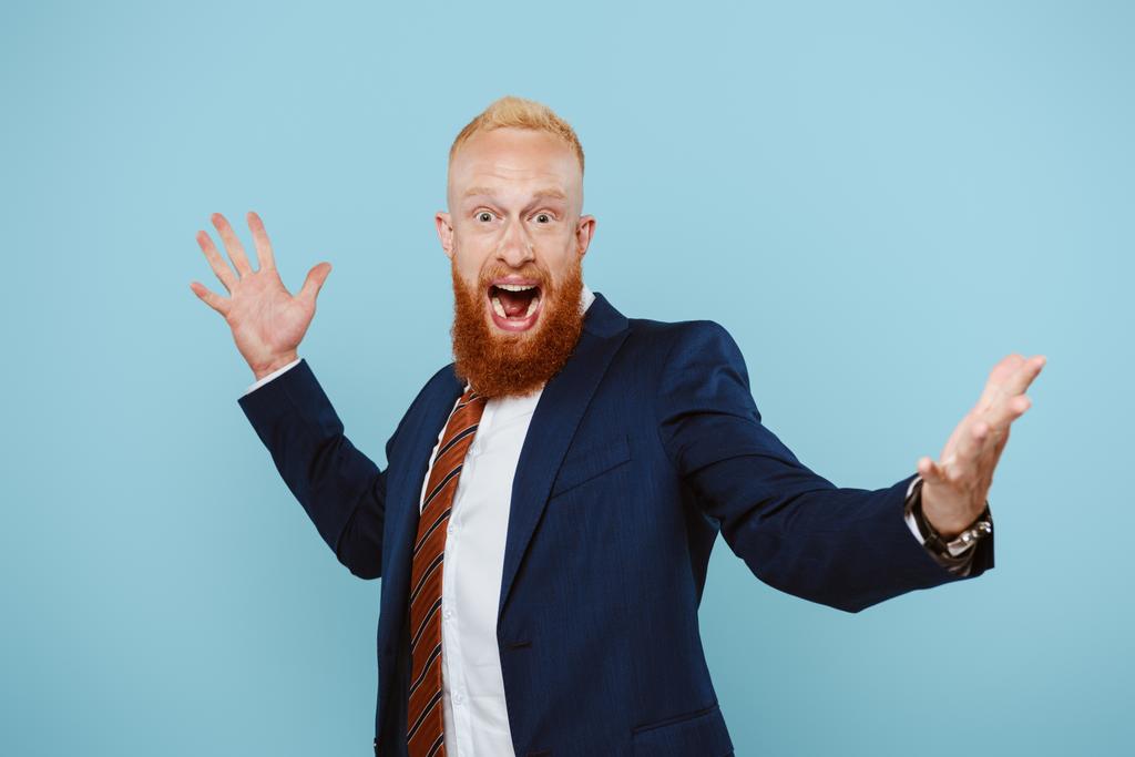 cheerful handsome businessman in suit celebrating and yelling isolated on blue - Photo, Image