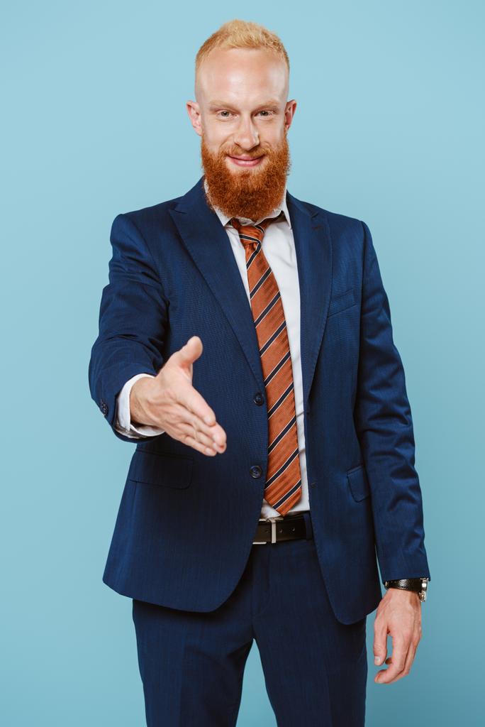 confiante sorridente barbudo empresário com mão para aperto de mão, isolado em azul
 - Foto, Imagem