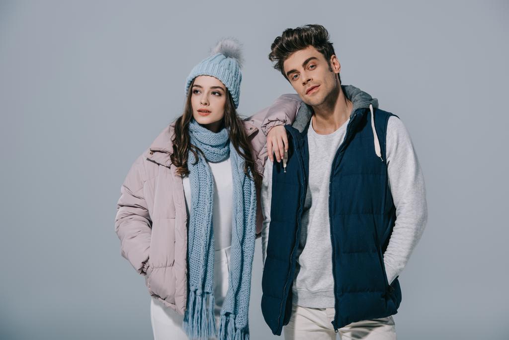 elegante pareja joven posando en traje de invierno, aislado en gris
 - Foto, imagen