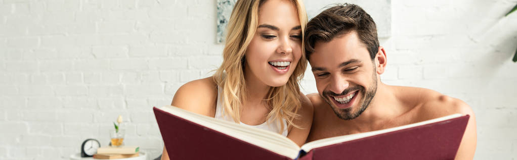 pareja emocionada leyendo libro juntos en la cama por la mañana
  - Foto, Imagen