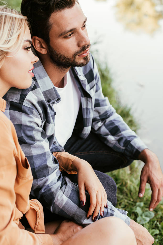 pareja joven soñadora mirando hacia otro lado mientras pasa tiempo cerca del lago
 - Foto, imagen