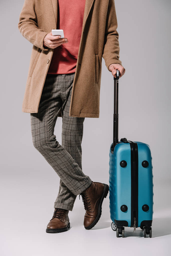 rajattu näkymä tyylikäs mies seisoo matkakassi ja älypuhelin harmaa
 - Valokuva, kuva