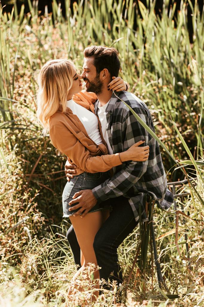 felice giovane coppia abbracciare e baciare in boscaglia di carice nel parco
 - Foto, immagini