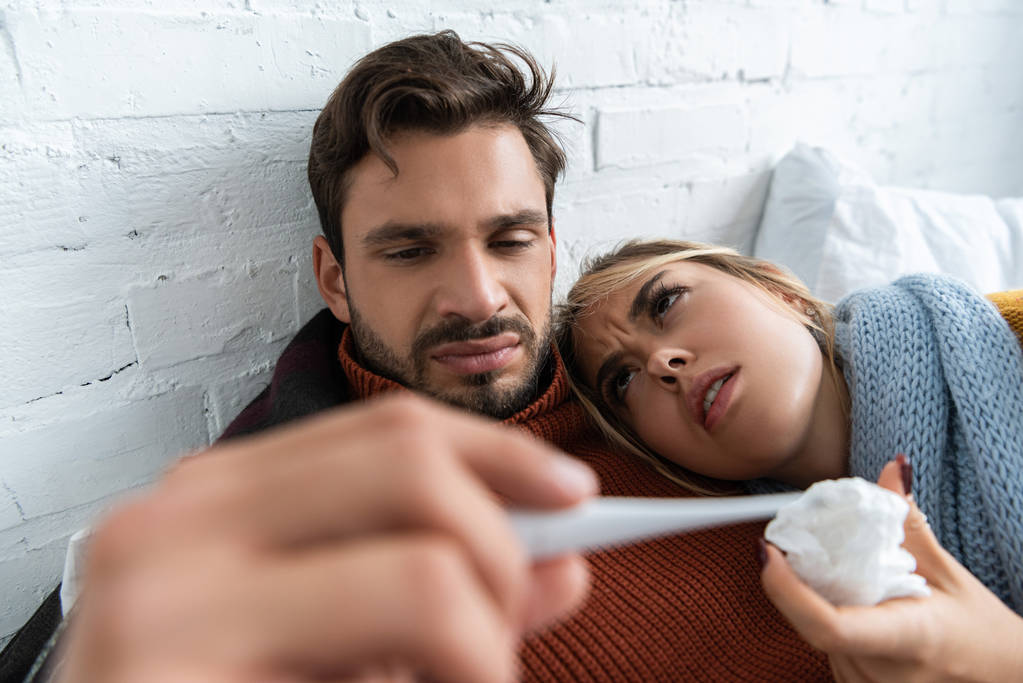 casal doente com febre segurando termômetro na cama
  - Foto, Imagem