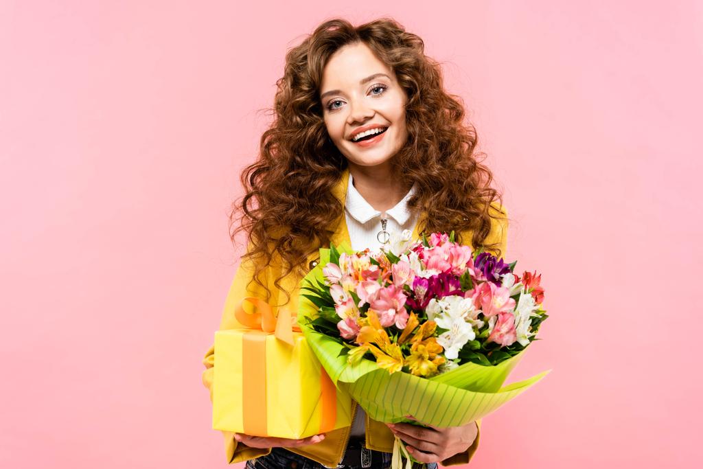 boldog göndör lány kezében ajándék doboz és csokor virág, elszigetelt rózsaszín - Fotó, kép