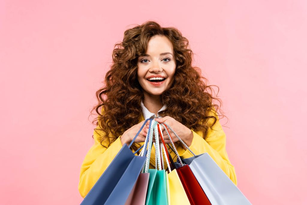 beautiful curly girl holding shopping bags, isolated on pink - Photo, Image
