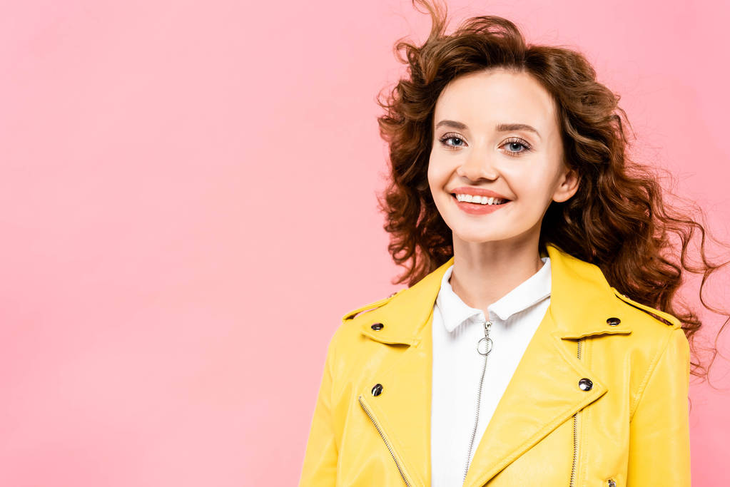 fashionable curly girl in yellow leather jacket, isolated on pink - 写真・画像