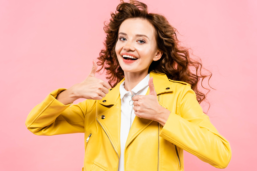 menina encaracolado na moda em jaqueta de couro amarelo mostrando polegares para cima, isolado em rosa
 - Foto, Imagem