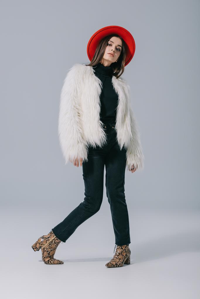 stylish elegant woman posing in white fur coat and red hat on grey - 写真・画像