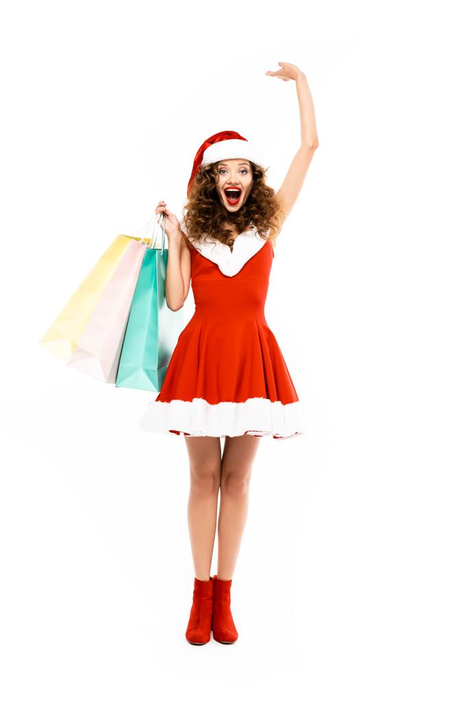 Noel Baba kostümlü güzel, heyecanlı bir kadın alışveriş torbalarıyla poz veriyor, beyaz tenli. - Fotoğraf, Görsel