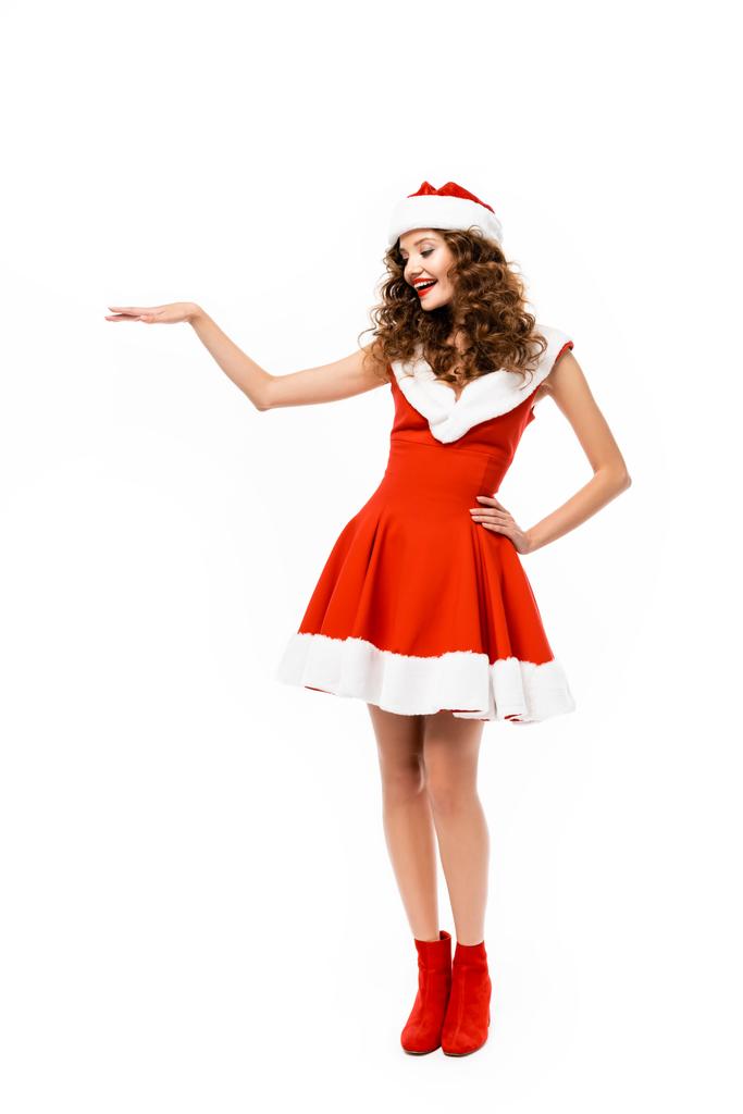 glückliches Mädchen posiert im Weihnachtsmannkostüm und präsentiert etwas, isoliert auf weiß - Foto, Bild