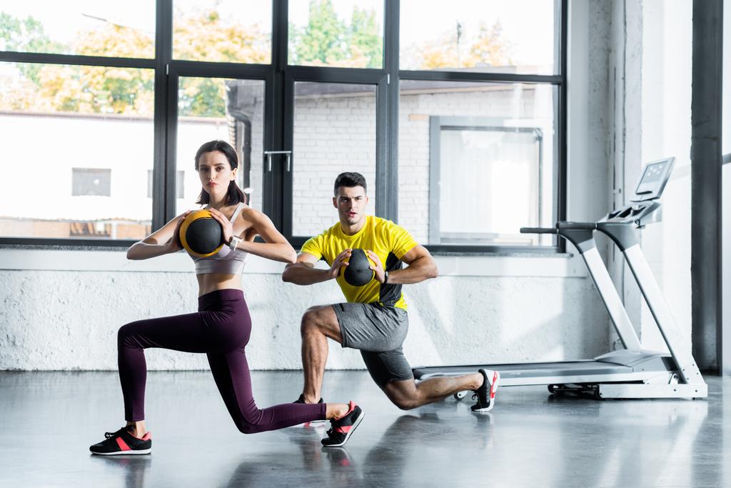 sportsman and sportswoman doing lunges with balls in sports center - Photo, Image
