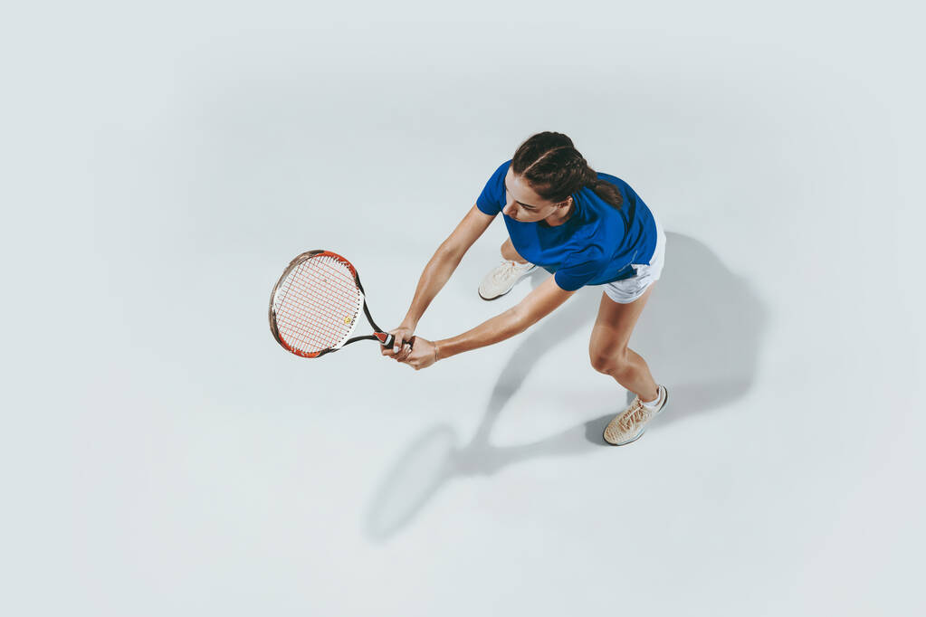 Mujer joven con camisa azul jugando tenis. Juventud, flexibilidad, poder y energía
. - Foto, imagen