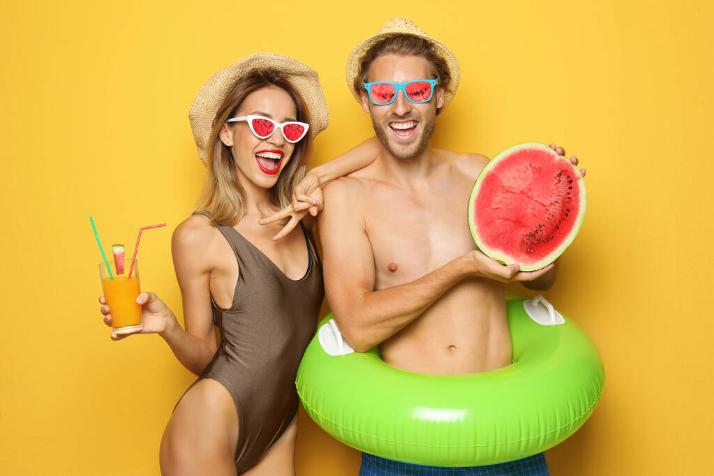 Feliz pareja joven en ropa de playa sobre fondo rosa. Gafas de sol de frutas como tendencia de verano
 - Foto, Imagen
