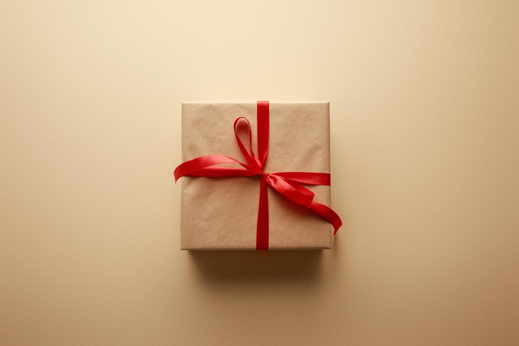 top view ajándék doboz kézműves papír piros szalaggal bézs háttér - Fotó, kép