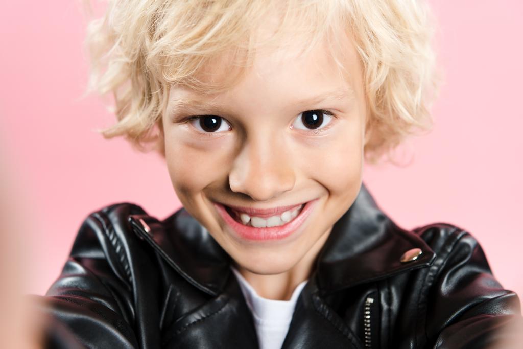 enfoque selectivo del niño sonriente mirando la cámara aislada en rosa
 - Foto, imagen