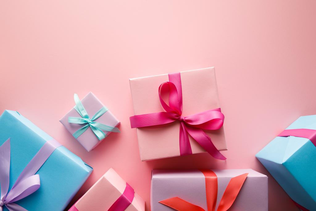 felső nézet színes ajándékdobozok szatén szalagok rózsaszín háttér - Fotó, kép