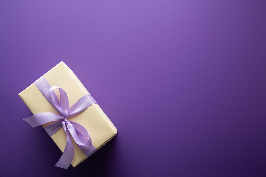 top view of gift box with violet ribbon on purple background with copy space - Photo, Image