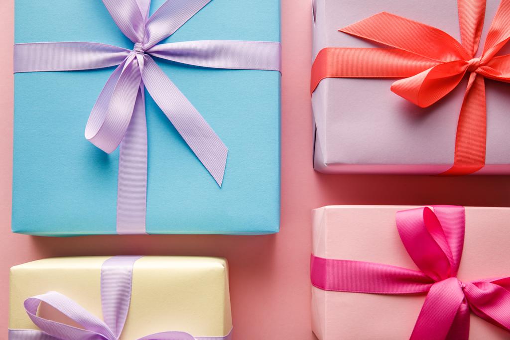πάνω όψη πολύχρωμα κουτιά δώρων με κορδέλες σε ροζ φόντο - Φωτογραφία, εικόνα