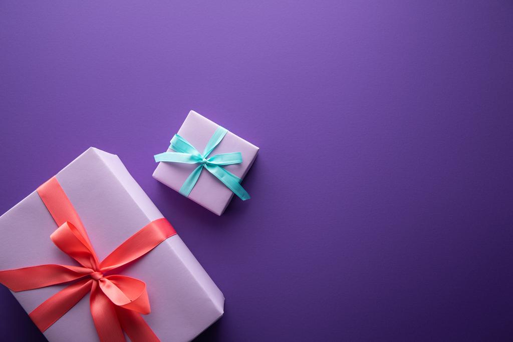 Renkli hediye kutularının üst görünümü kurdeleli ve mor arkaplanlı ve kopyalama alanı olan fiyonklar - Fotoğraf, Görsel
