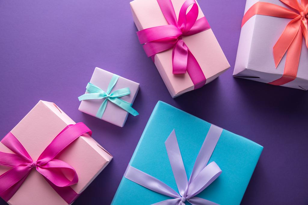 top view of colorful gift boxes with ribbons and bows on purple background - Photo, Image
