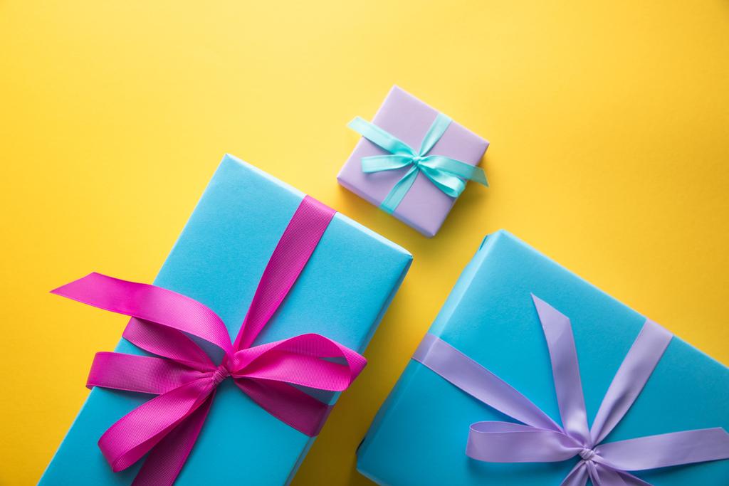top view of colorful gift boxes with ribbons on yellow background - Photo, Image