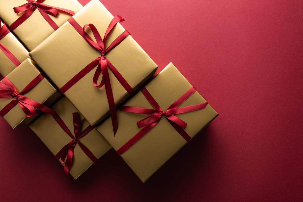 Ansicht der goldenen Geschenkboxen mit Bändern auf rotem Hintergrund - Foto, Bild