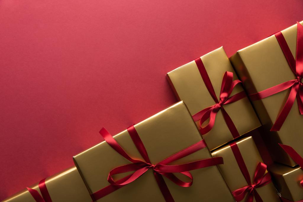 vista dall'alto di scatole regalo dorate con nastri su sfondo rosso con spazio copia
 - Foto, immagini