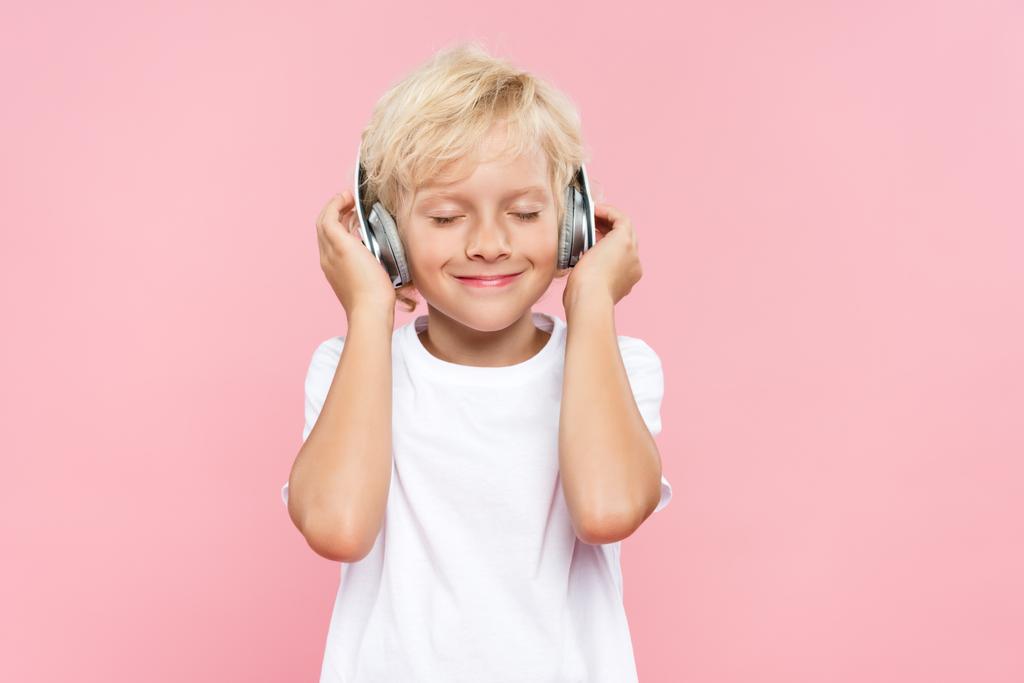 enfant souriant avec écouteurs écoutant de la musique isolée sur rose
 - Photo, image