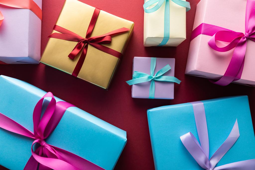 top view of colorful gift boxes with ribbons on red background - Photo, Image