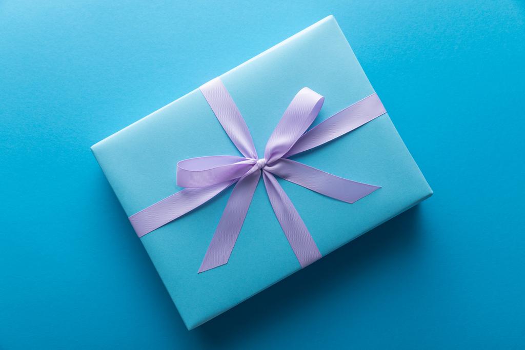Ansicht der Geschenkbox mit violettem Band auf blauem Hintergrund - Foto, Bild