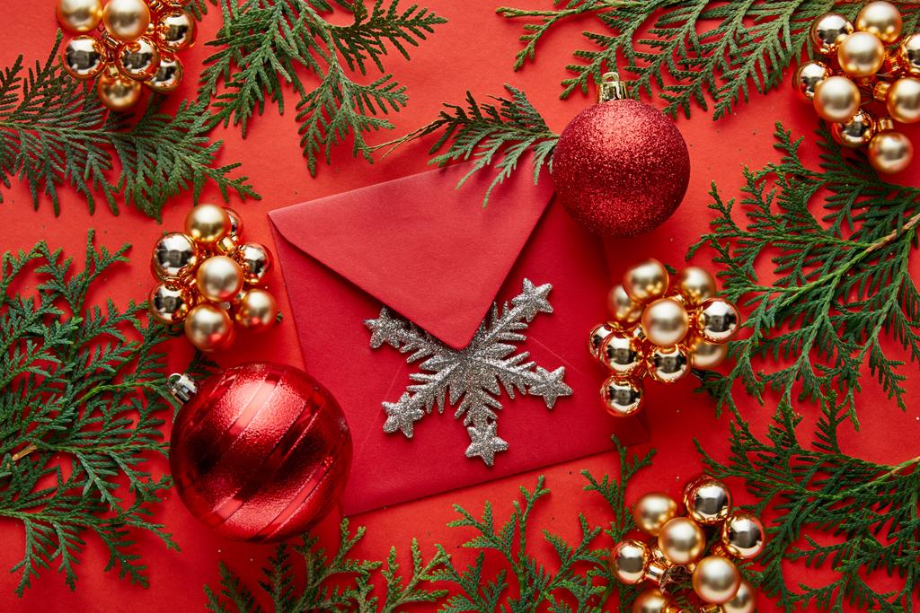 vista superior de la decoración de Navidad brillante, sobre con copo de nieve y thuja sobre fondo rojo
 - Foto, Imagen