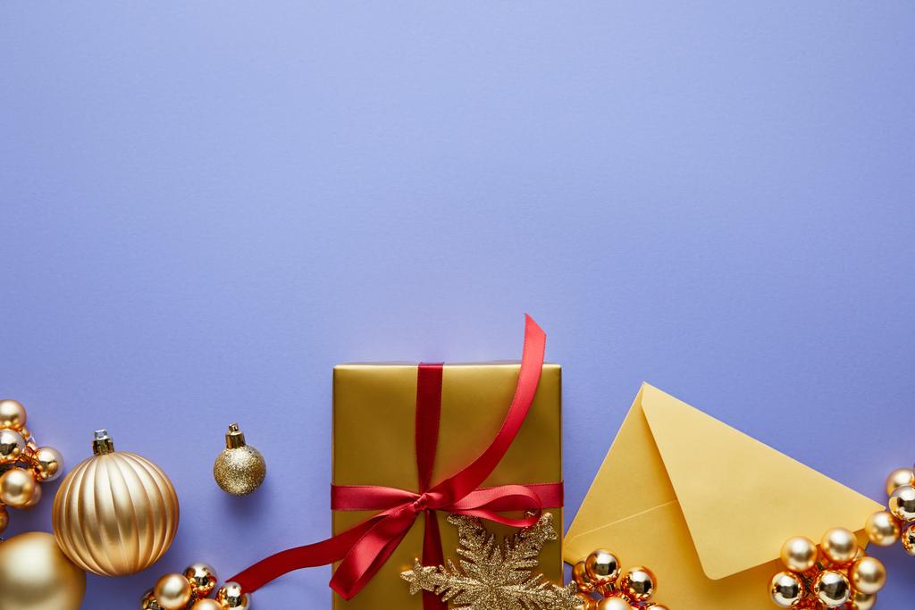Blick von oben auf goldglänzende Weihnachtsdekoration, Umschlag und Geschenkbox auf blauem Hintergrund - Foto, Bild
