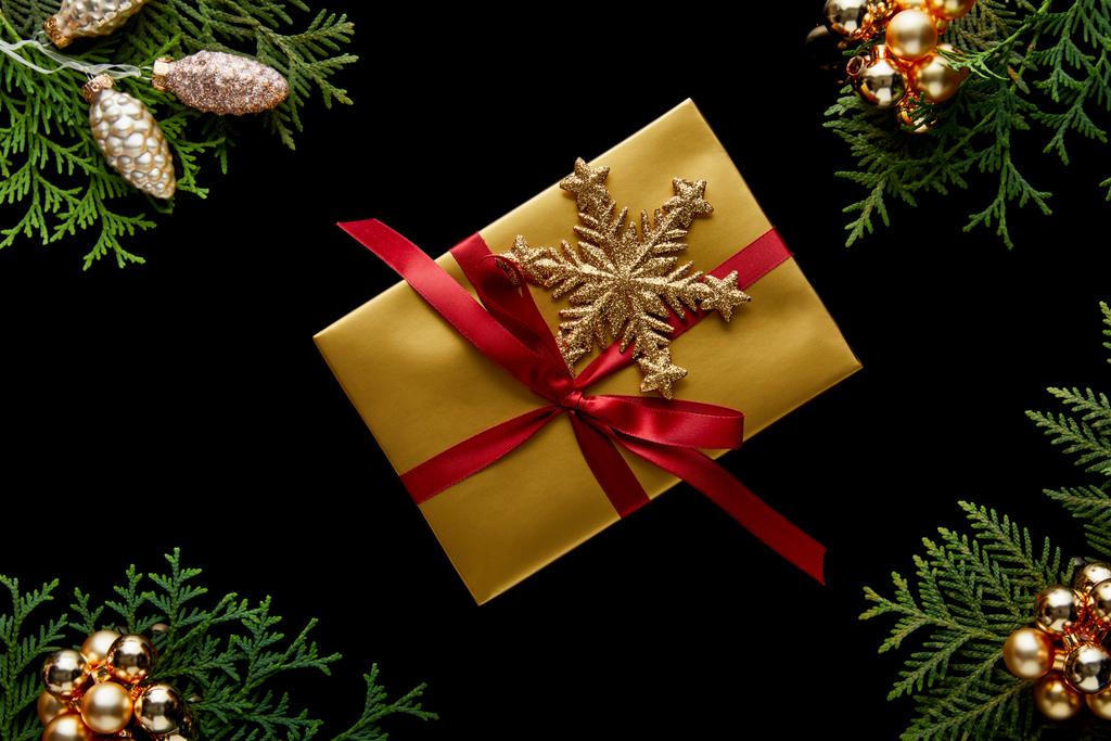 vista superior de brillante decoración de Navidad dorada, ramas de thuja verde y regalo aislado en negro
 - Foto, imagen