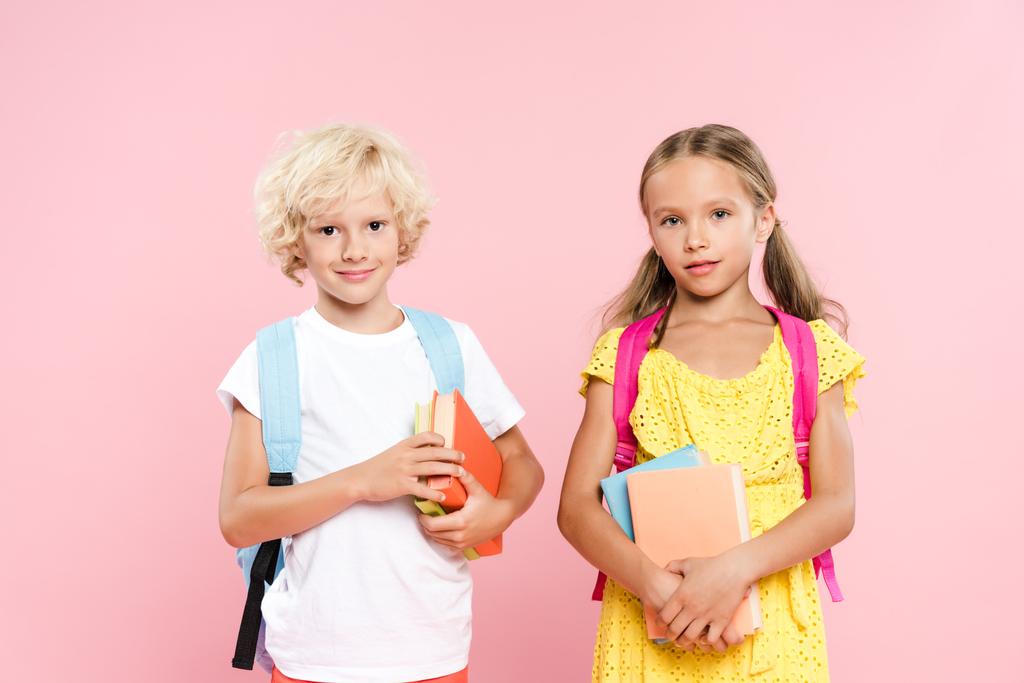 écoliers souriants avec sacs à dos contenant des livres isolés sur rose
 - Photo, image