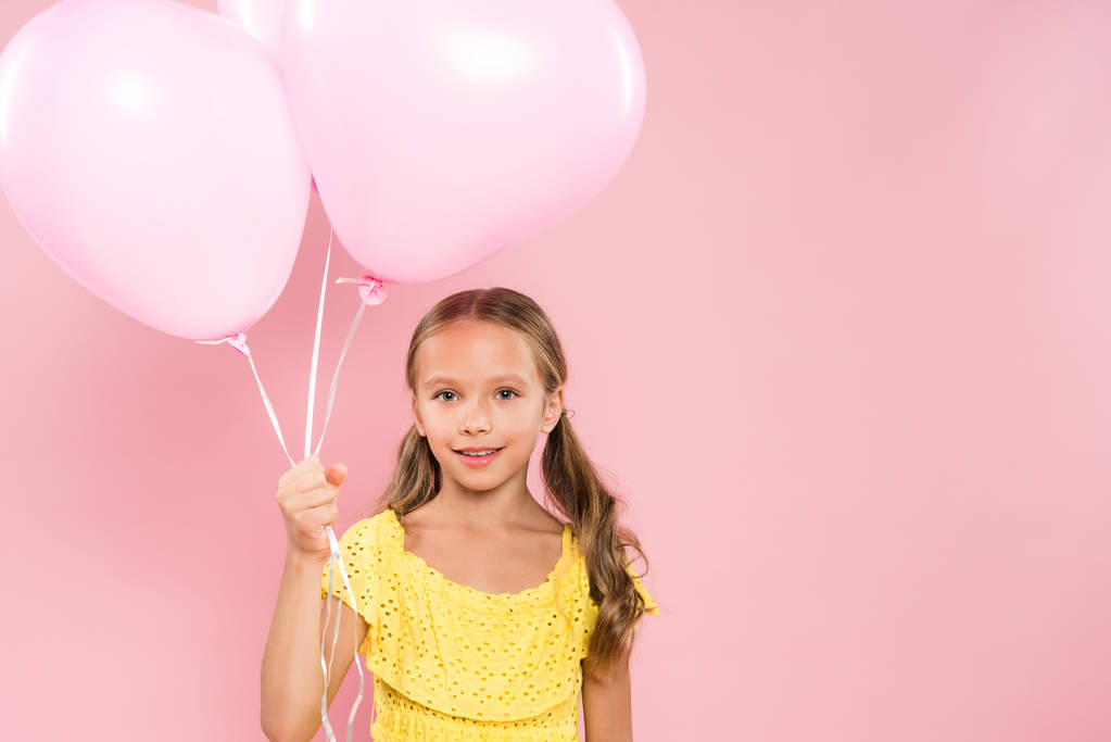 enfant souriant et mignon tenant des ballons sur fond rose
  - Photo, image
