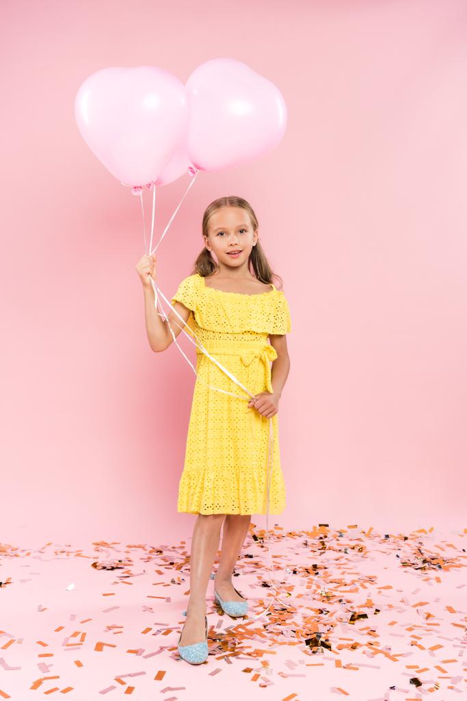 sonriente y lindo niño sosteniendo globos sobre fondo rosa
  - Foto, imagen