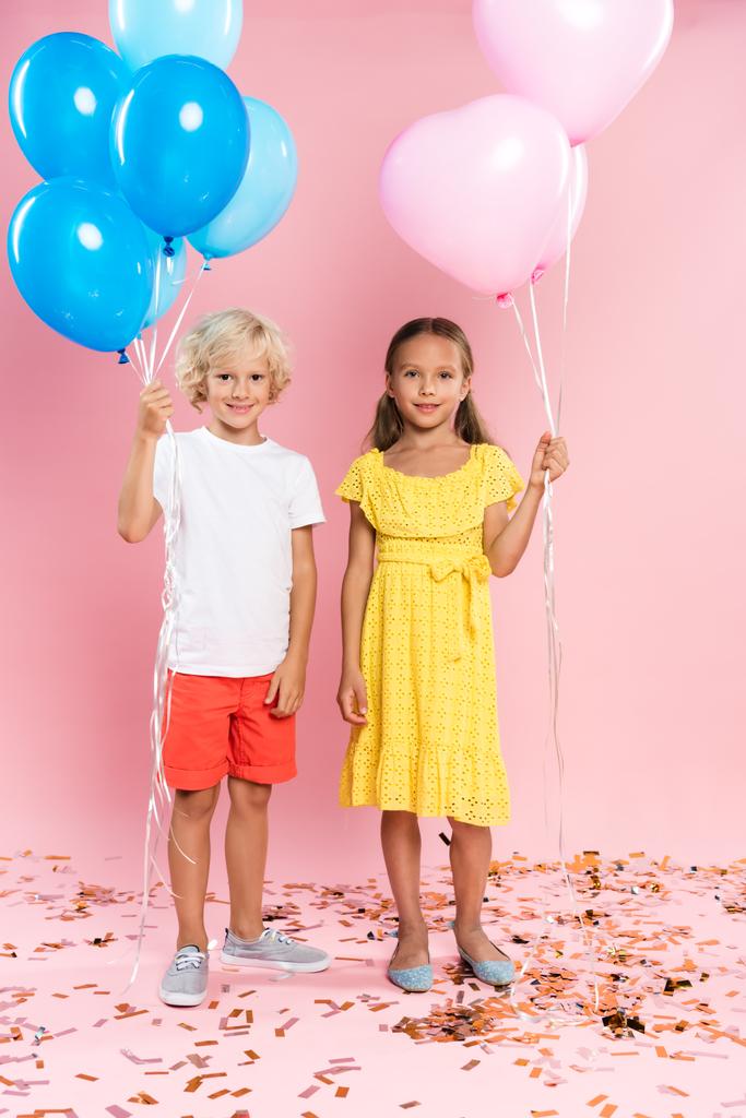 ピンクを背景に風船を抱えた笑顔でかわいい子供たち  - 写真・画像