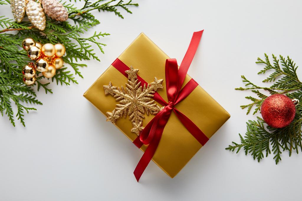 felülnézet fényes arany és piros karácsonyi dekoráció zöld thuja ágak, csomagolt ajándék hópelyhek elszigetelt fehér - Fotó, kép