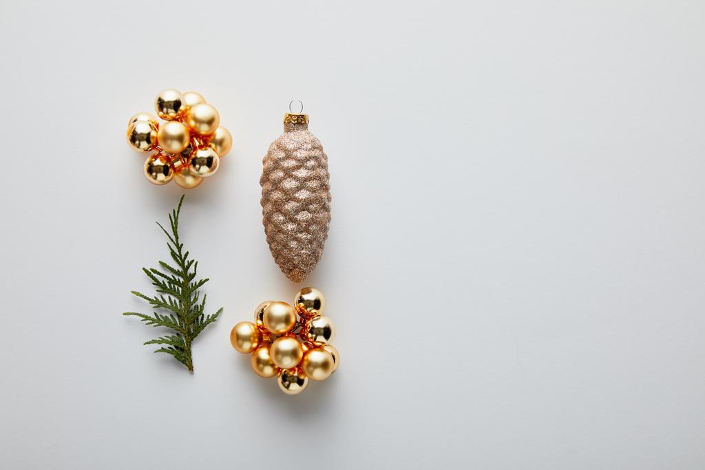 コピースペースと白に隔離された光沢のある黄金のクリスマスの装飾と緑のthujaの枝とフラットレイ - 写真・画像